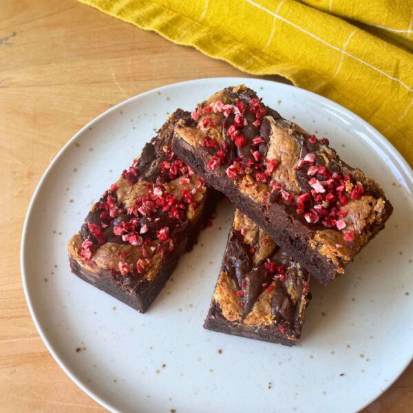 Chocolate brownies with raspberry topping on plate.