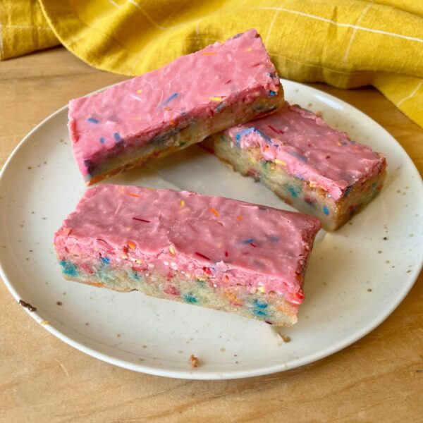 Three colourful iced slices on a white plate.